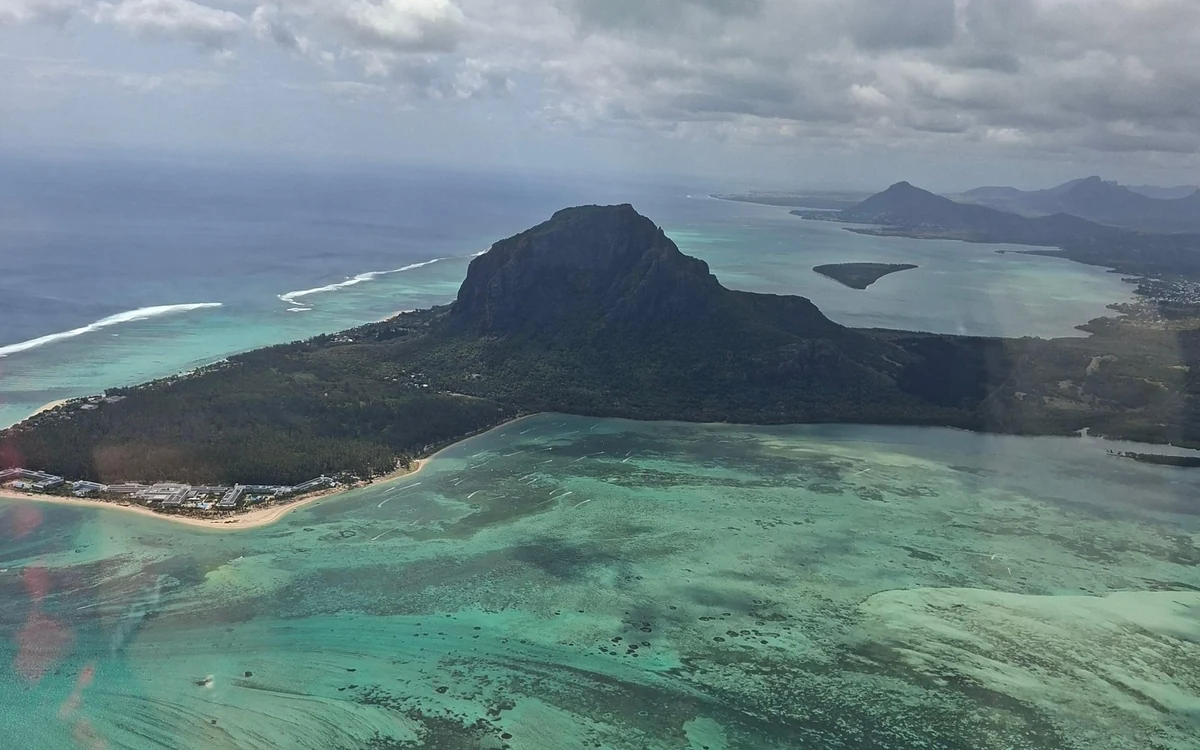 Le Morne Brabant che si erge sopra la sua penisola, fotografato attraverso il finestrino di un elicottero con la barriera corallina e la laguna intorno