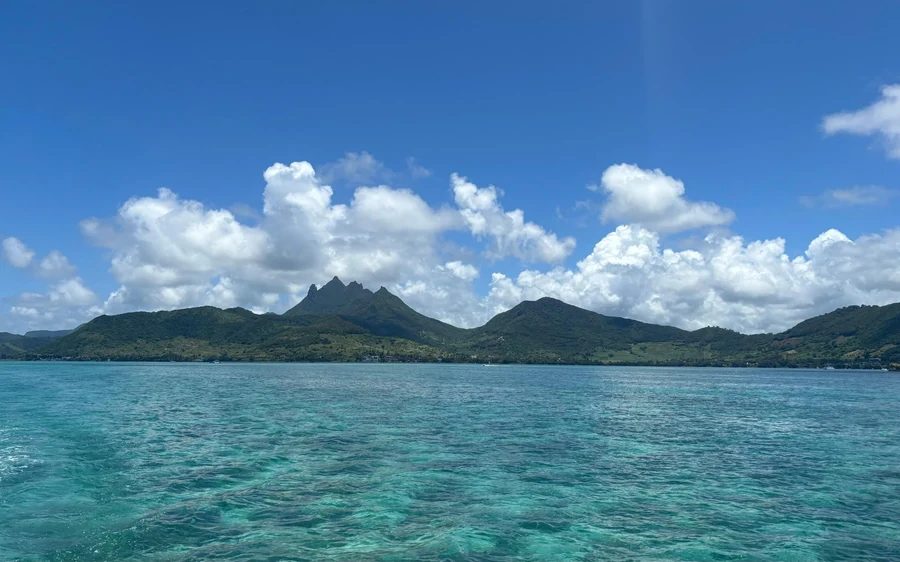 Eau turquoise peu profonde avec des collines vertes sur la rive opposée