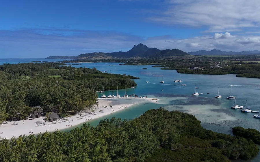 Une île plate et verte dans le lagon avec un pic lointain au-delà