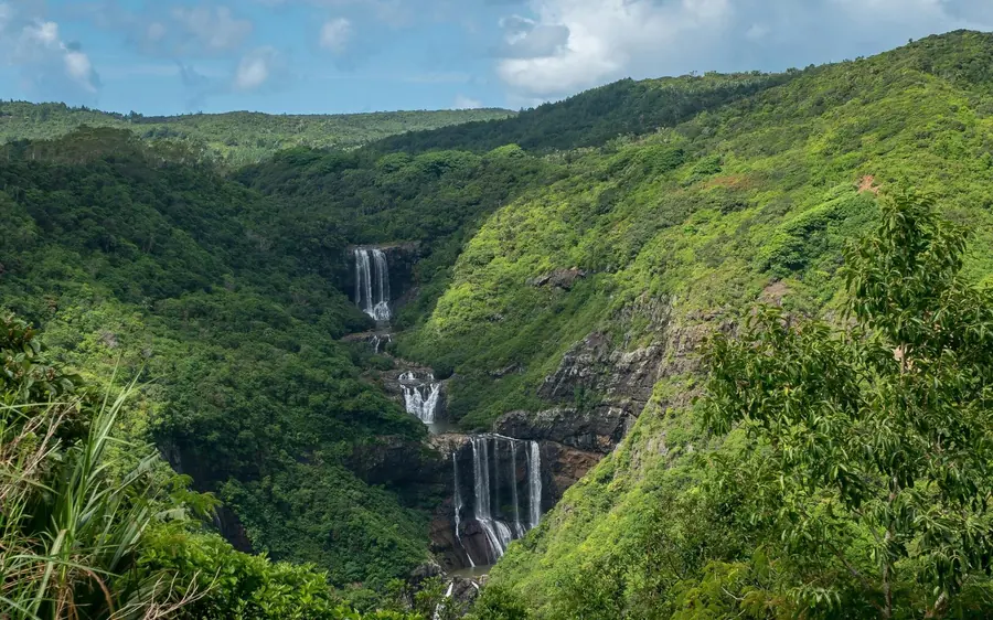De grandes cascades tombant de falaises vertes dans la forêt